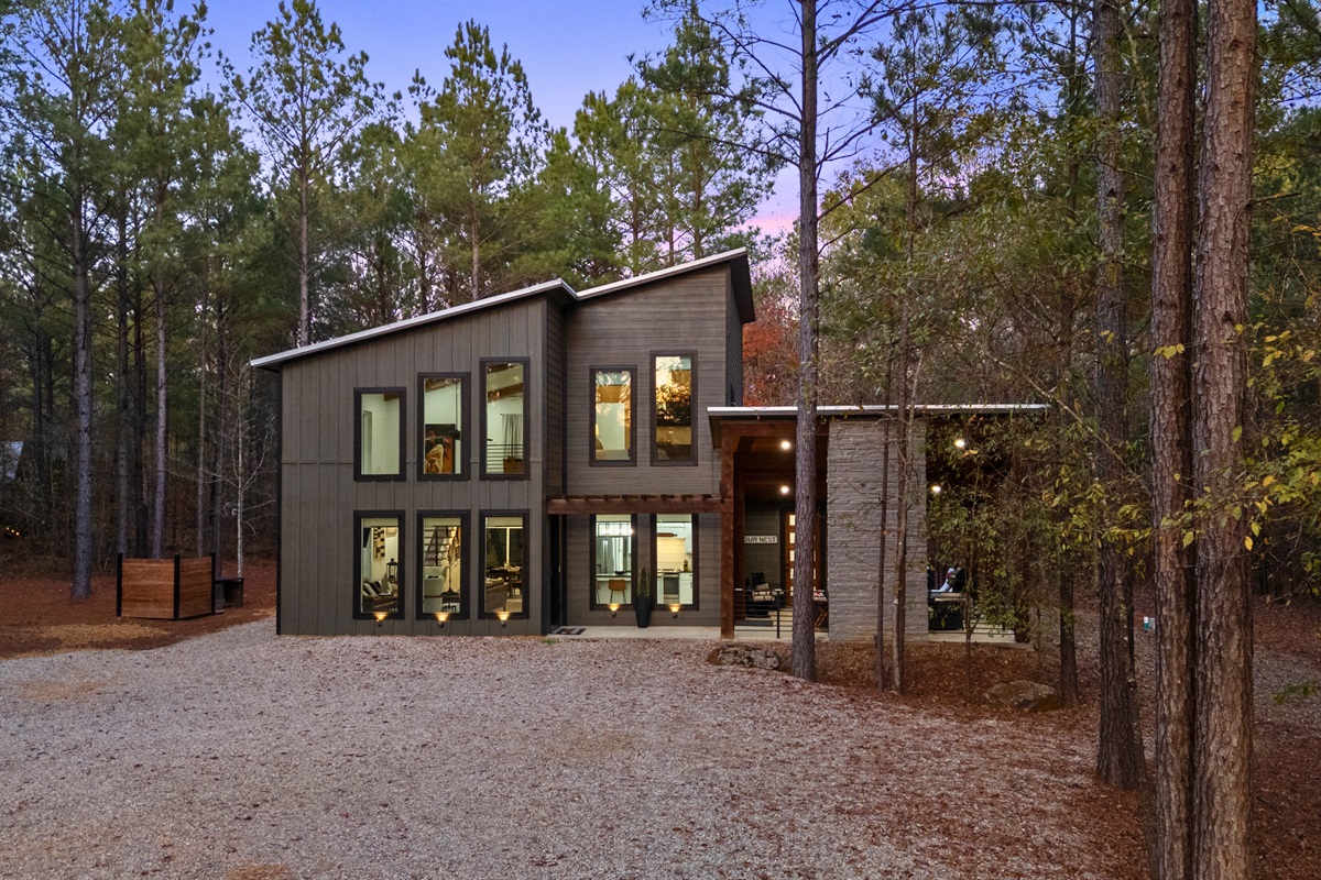 This exterior view highlights the modern architecture set against a peaceful wooded backdrop.