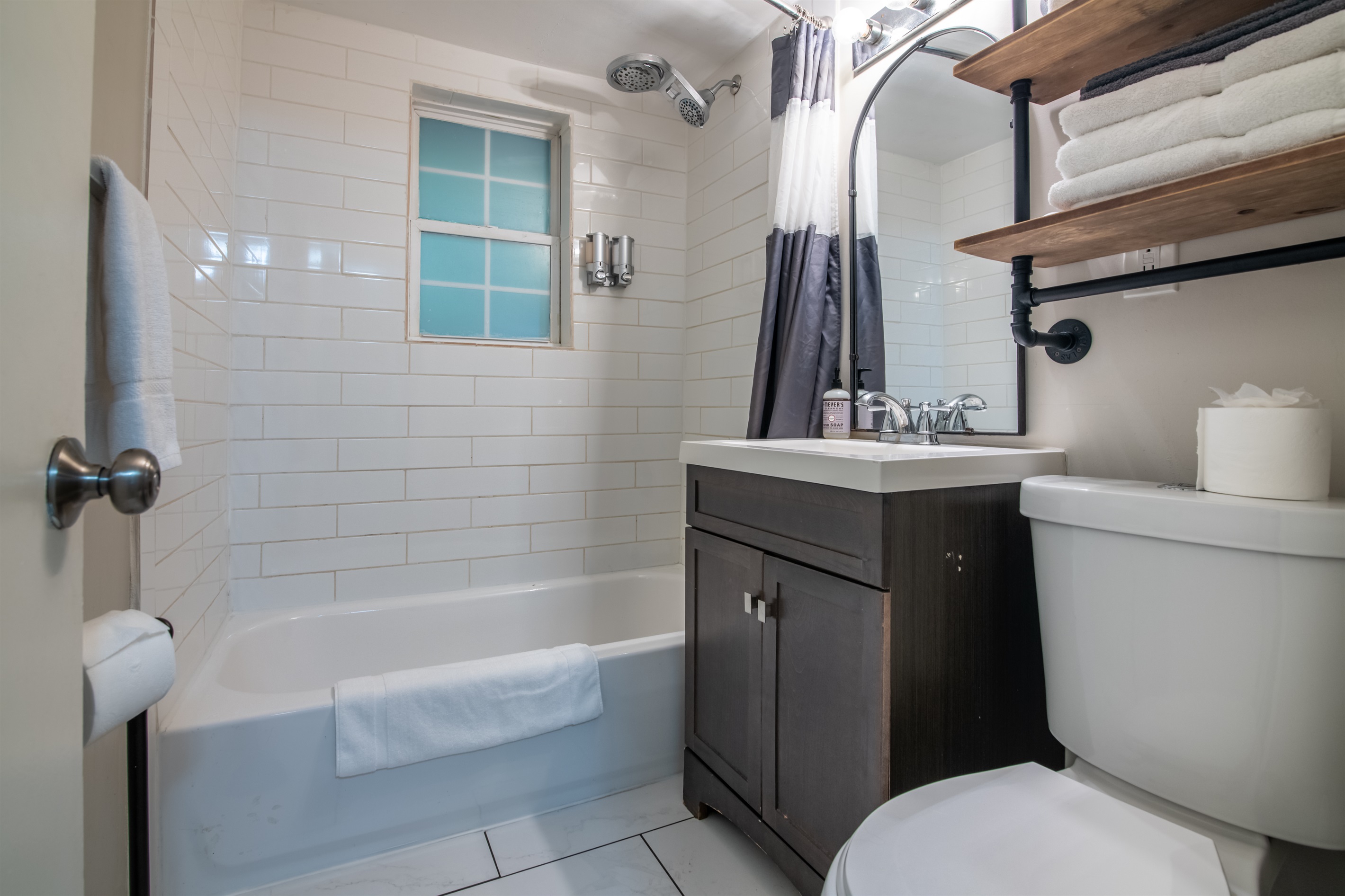 Clean, bright bathroom with full tub, shower, and modern vanity for your comfort.