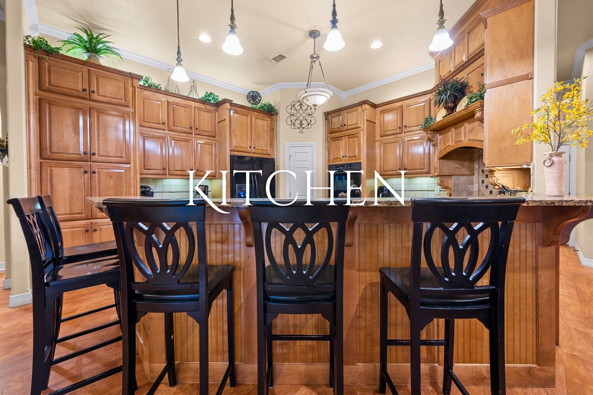 Spacious kitchen with granite countertops and bar seating.