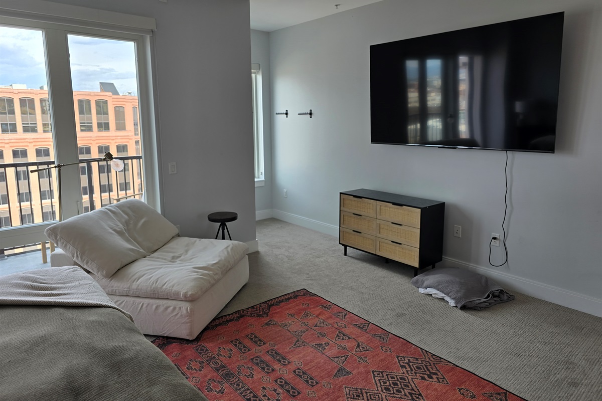 King size bed, extra seating area, clothes hanging in nook off of the main bedroom.