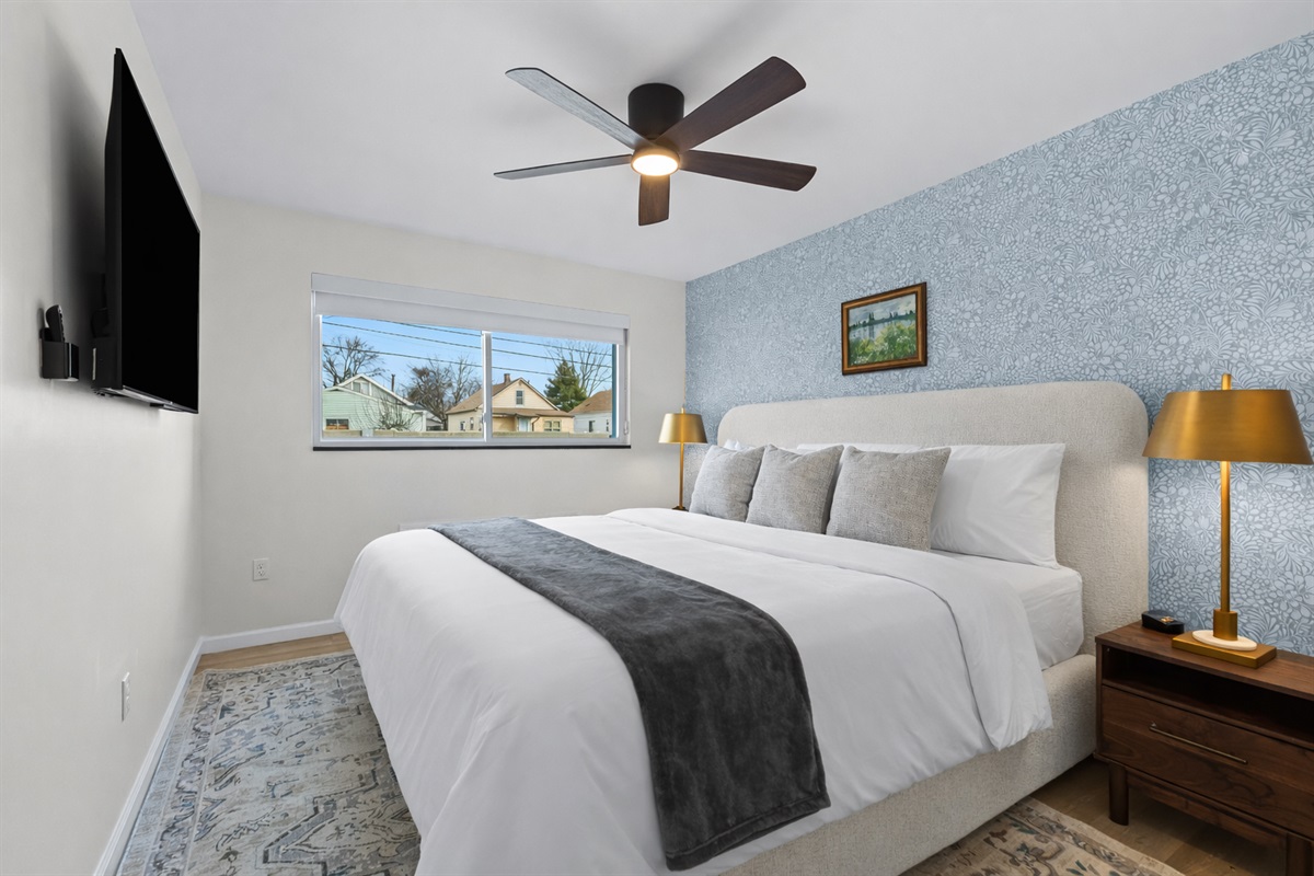 Unwind in this serene bedroom with a plush bed, soft linens, ceiling fan, and smart TV—designed for restful nights and relaxed mornings.