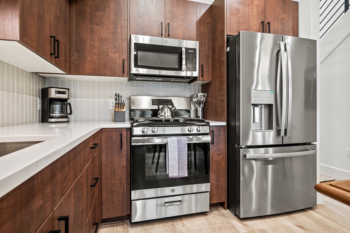 Cook with ease using stainless steel appliances, including a gas stove, large fridge, and microwave.