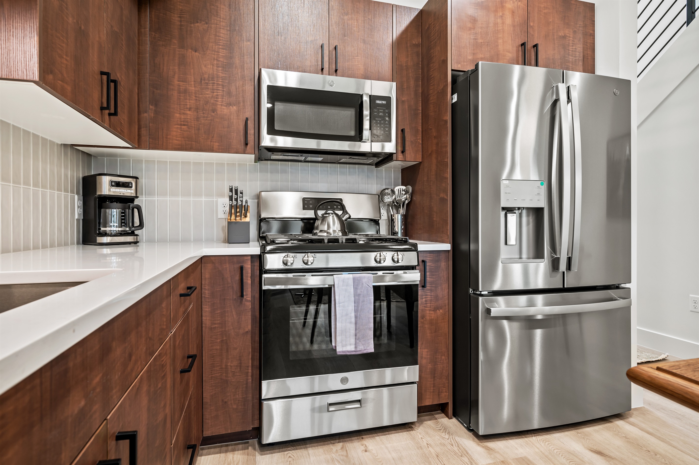 Cook with ease using stainless steel appliances, including a gas stove, large fridge, and microwave.