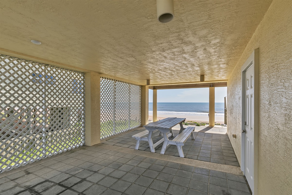 Walkway on ground floor has picnic table goes to beach, and access to interior