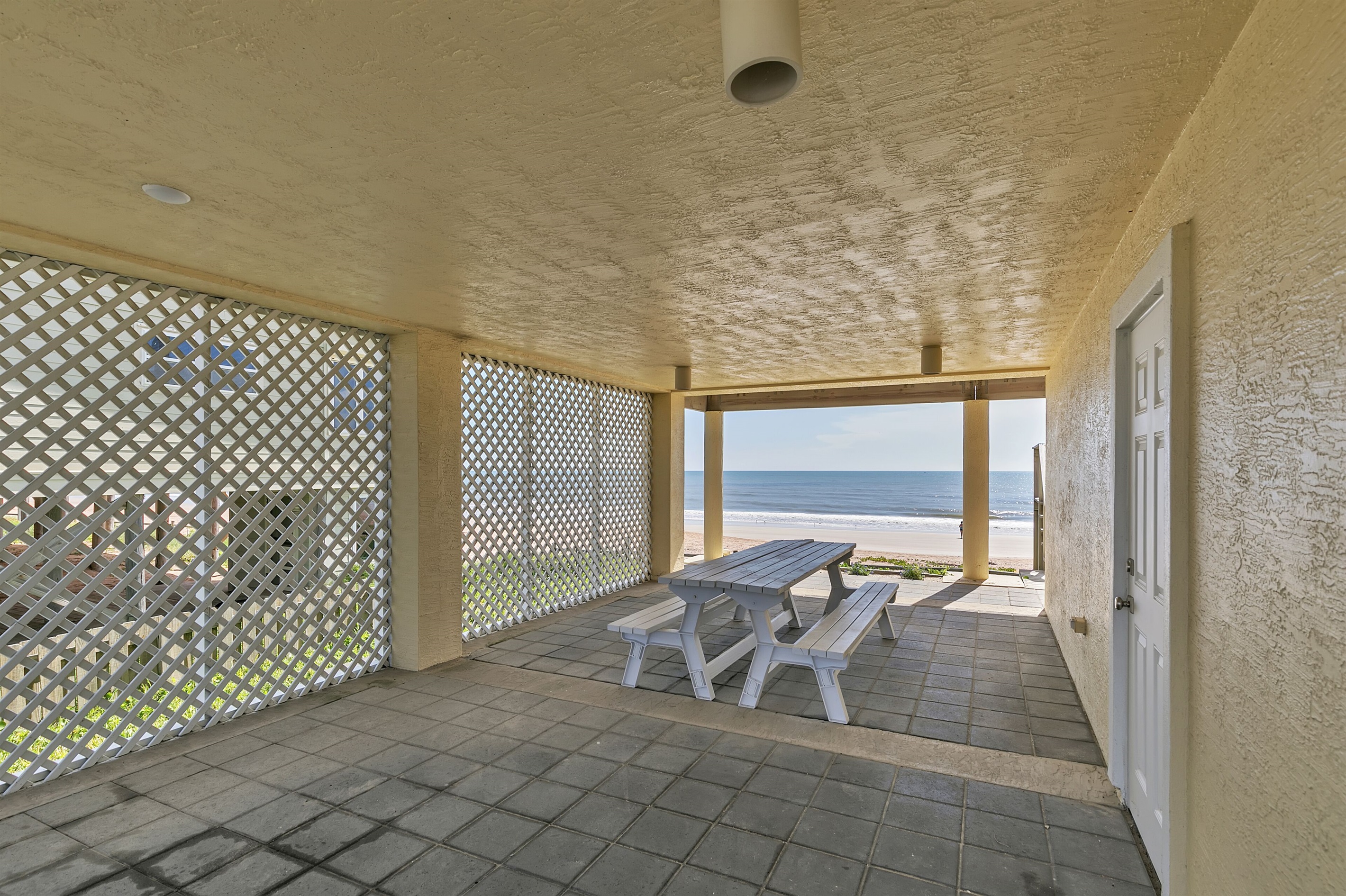 Walkway on ground floor has picnic table goes to beach, and access to interior