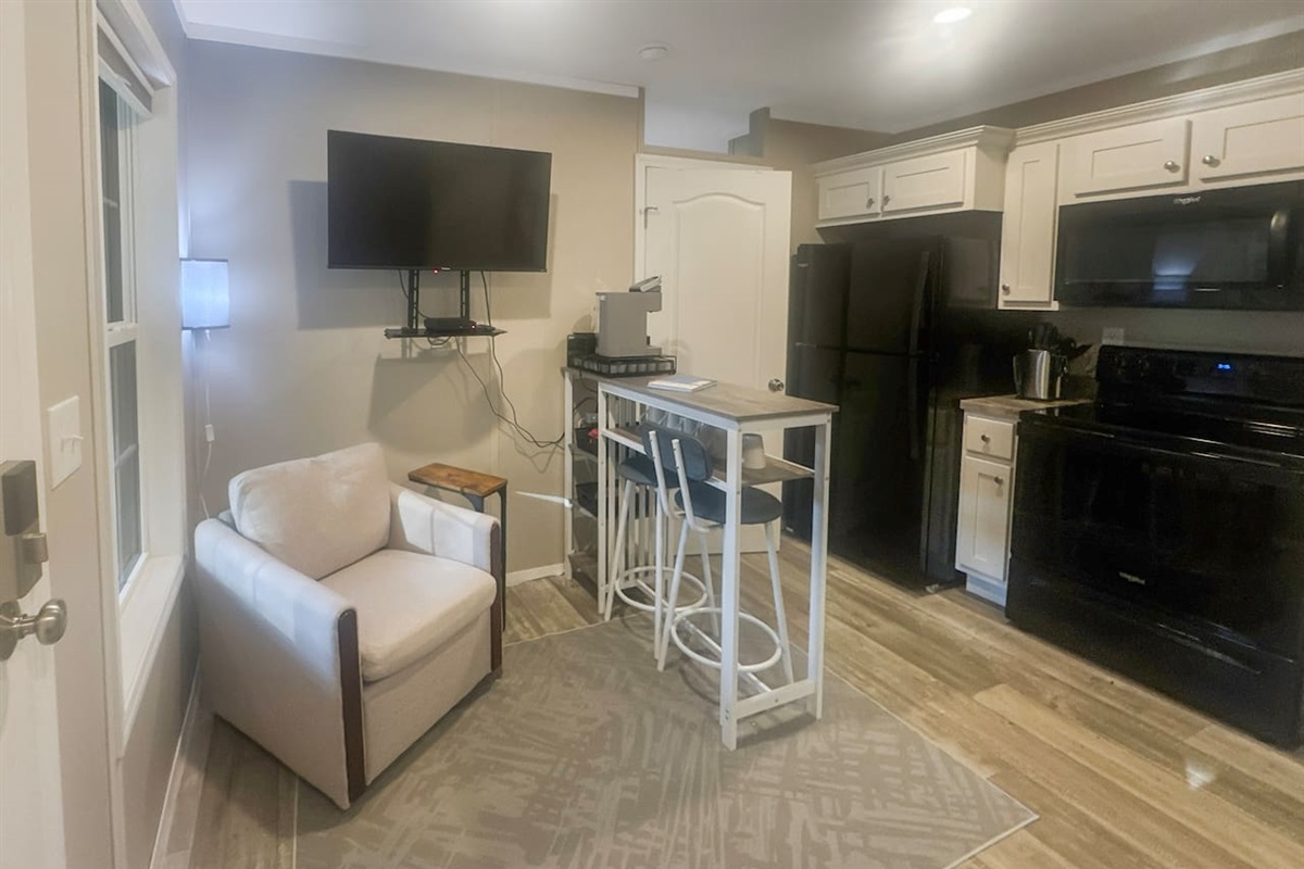 Smart tv with dvd player and dining area in living room. Full kitchen with refrigerator and stove.