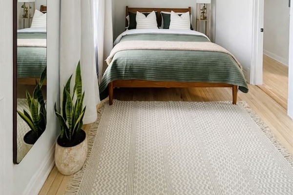 Spacious bedroom with modern decor and wood flooring.
