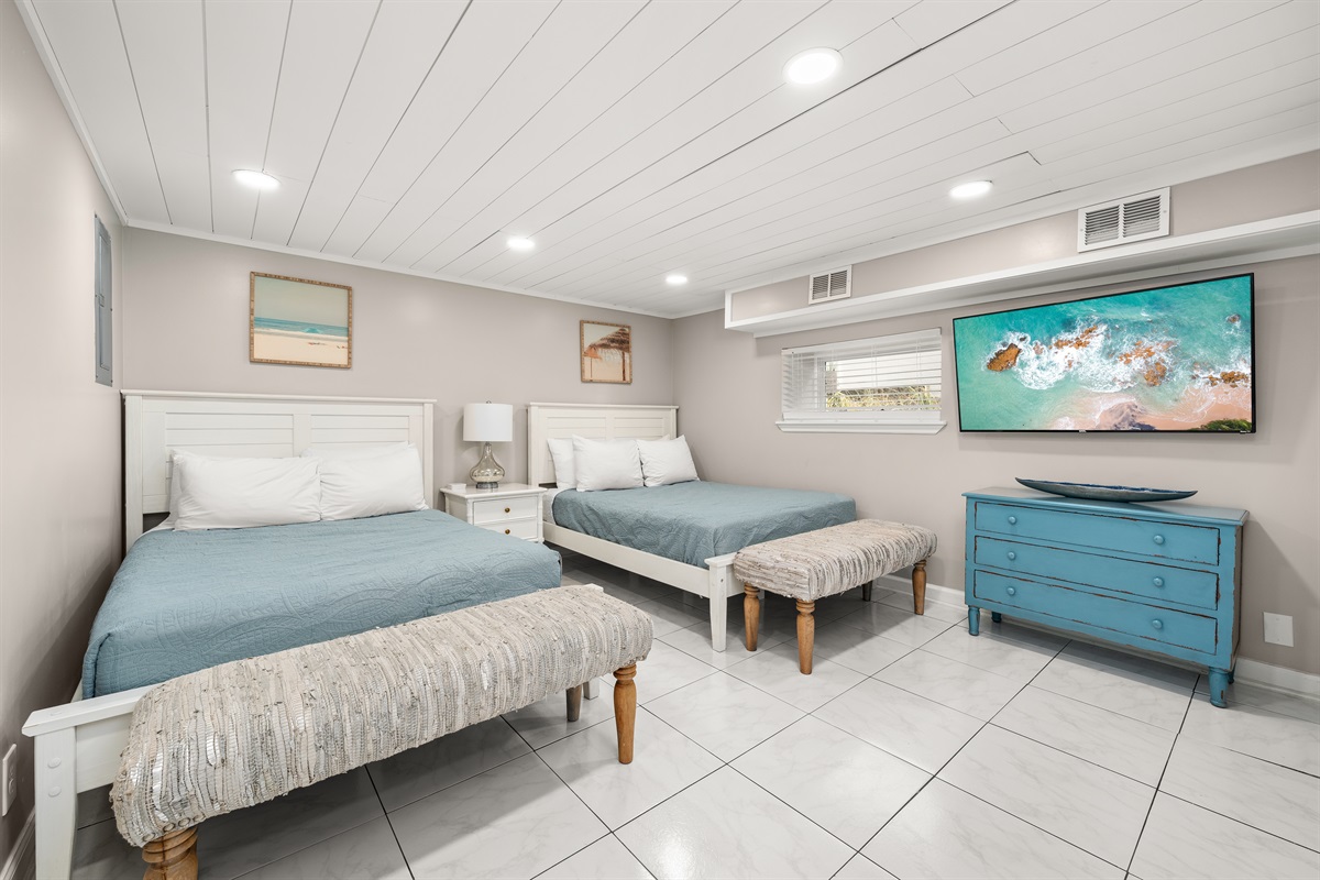 With two full beds, this hall bedroom downstairs can accommodate up to 4 guests. A 55" Roku-enabled TV is available for entertainment, with benches at the foot of each bed.