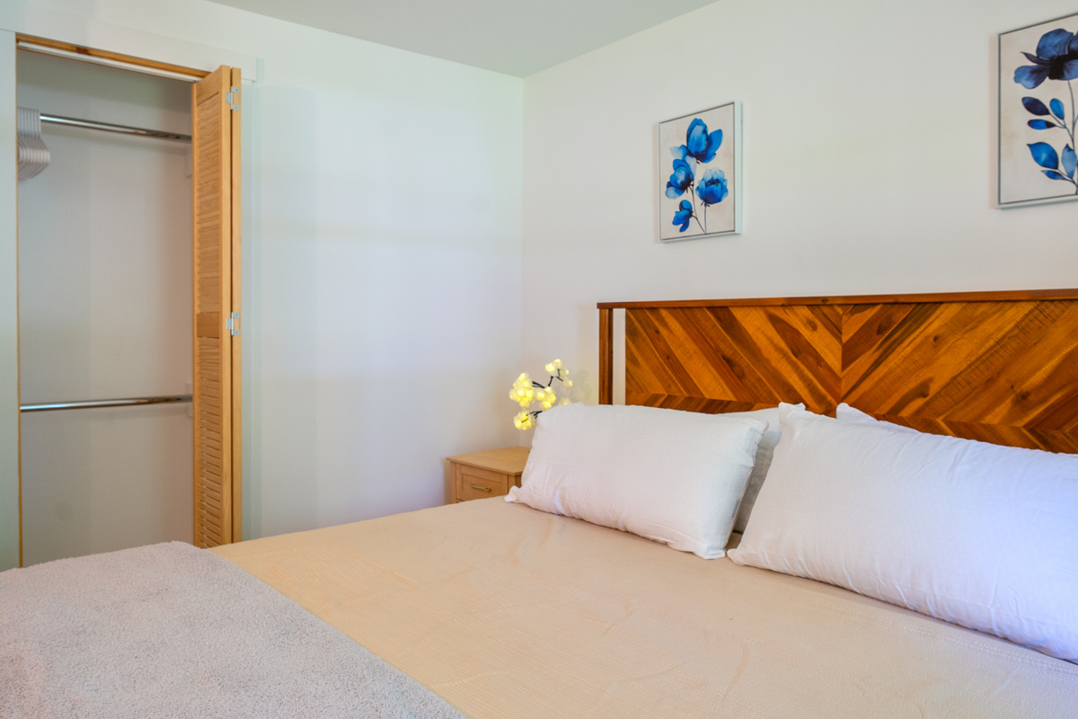 Unpack easily using the spacious built-in closet featured in the king bedroom. This angle showcases the functional bifold wooden louvers, dual hanging rods with clothing hangers, and convenient placement right next to the bed area.