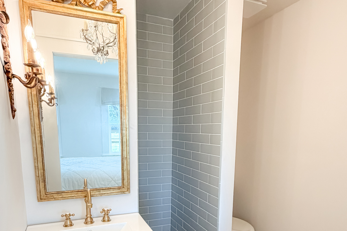 Elegant master bathroom with an ornate vintage mirror, warm lighting, and timeless designer details.