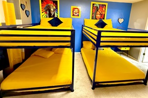 The bunk bedroom is a fun, functional space for kids and guests, featuring a cheerful yellow and blue color scheme with colorful artwork. The bunk beds maximize space and offer a cozy sleeping arrangement, creating more room for play and activities.