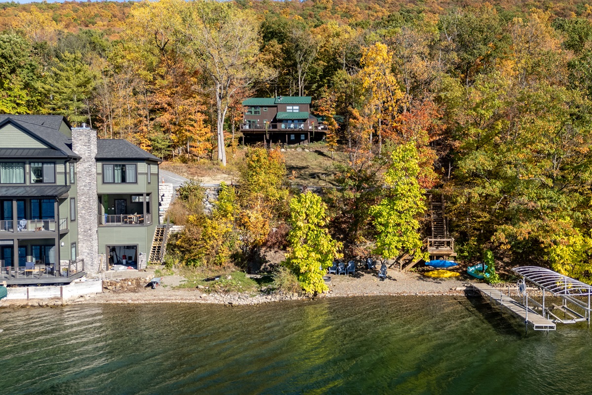 Wide lakeside view showing cabin up the hill, forest, and water together.