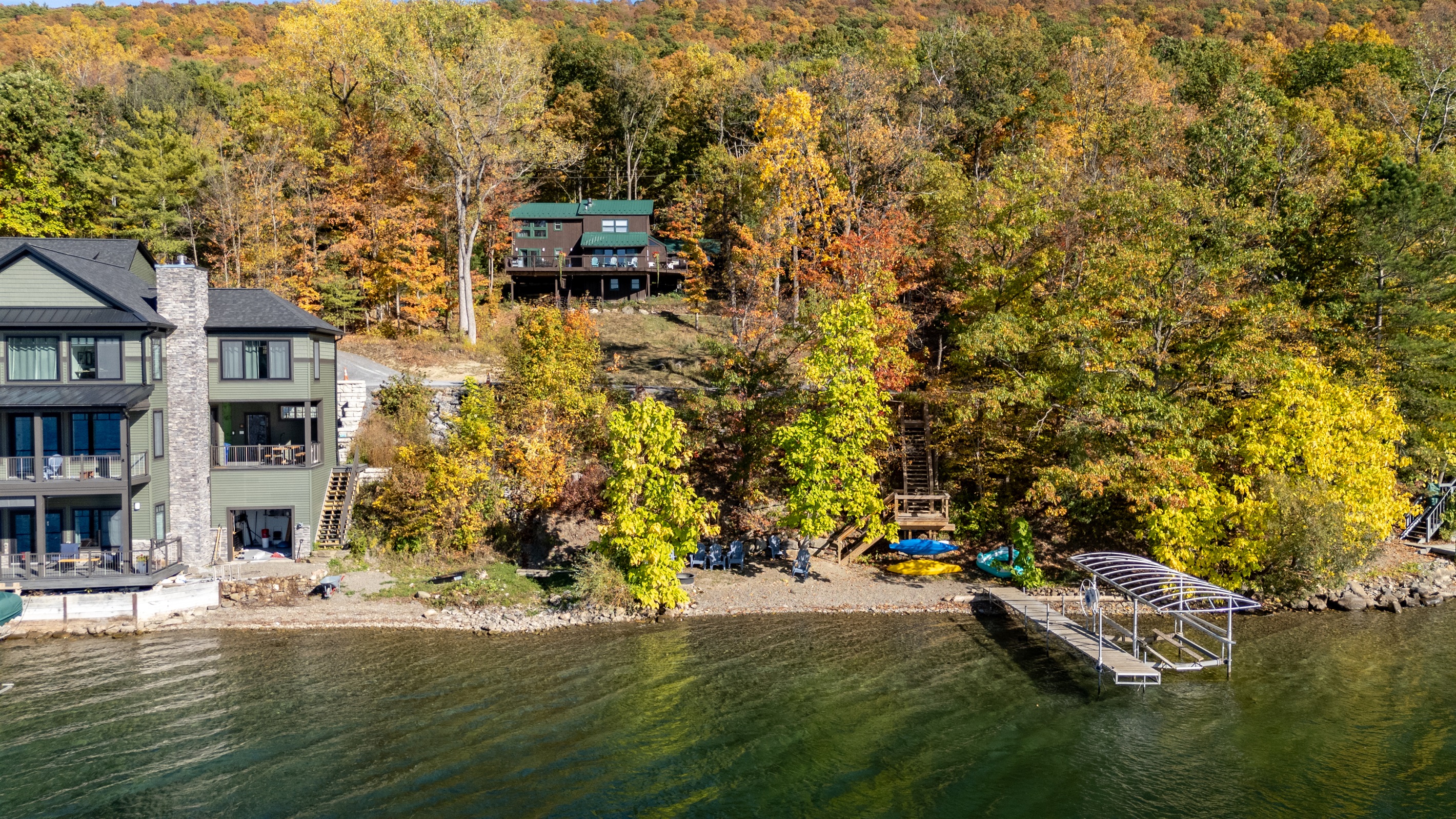 Wide lakeside view showing cabin up the hill, forest, and water together.