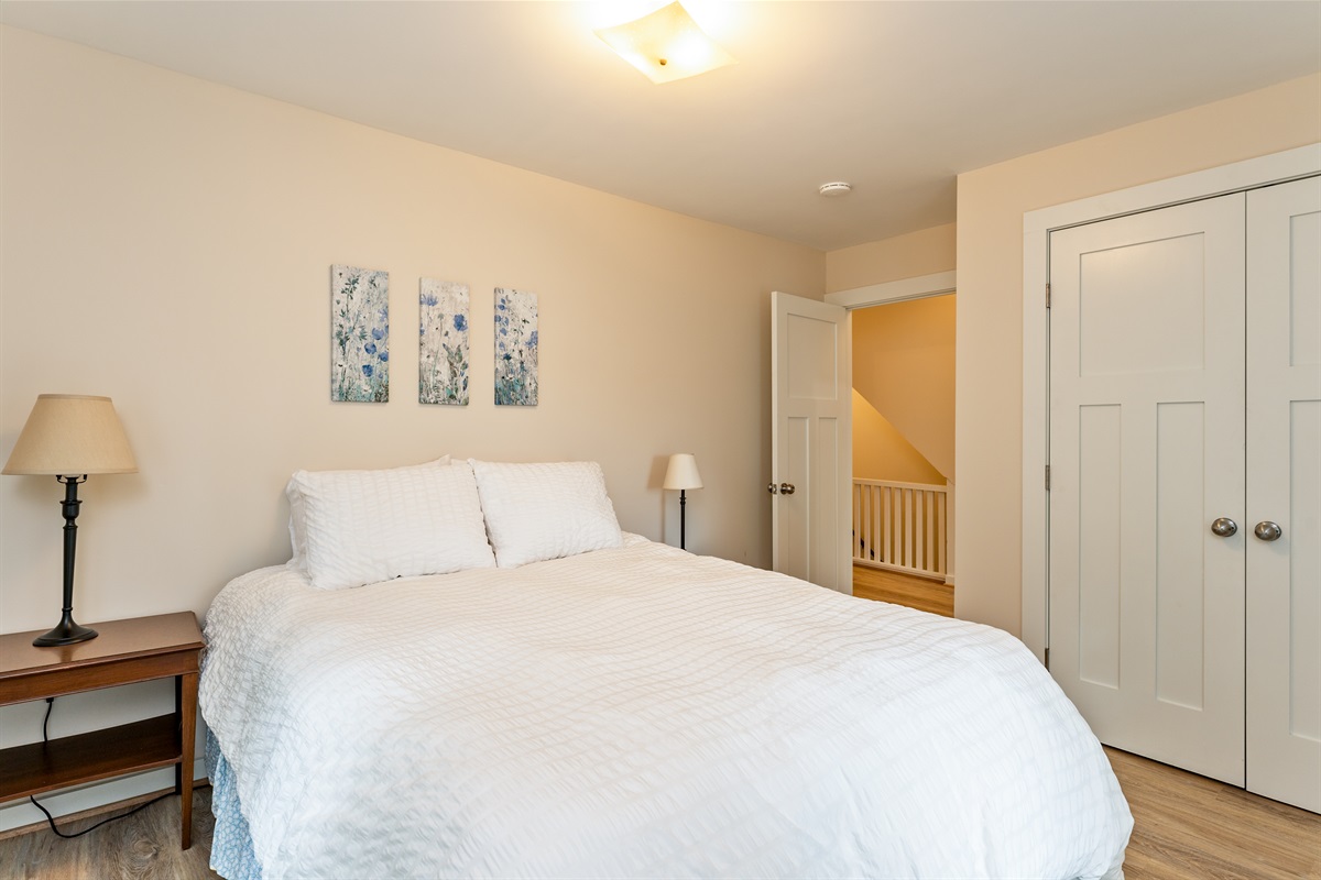 Inviting bedroom with serene views, soft natural light, and a plush white comforter for restful nights. Bedroom #1 queen