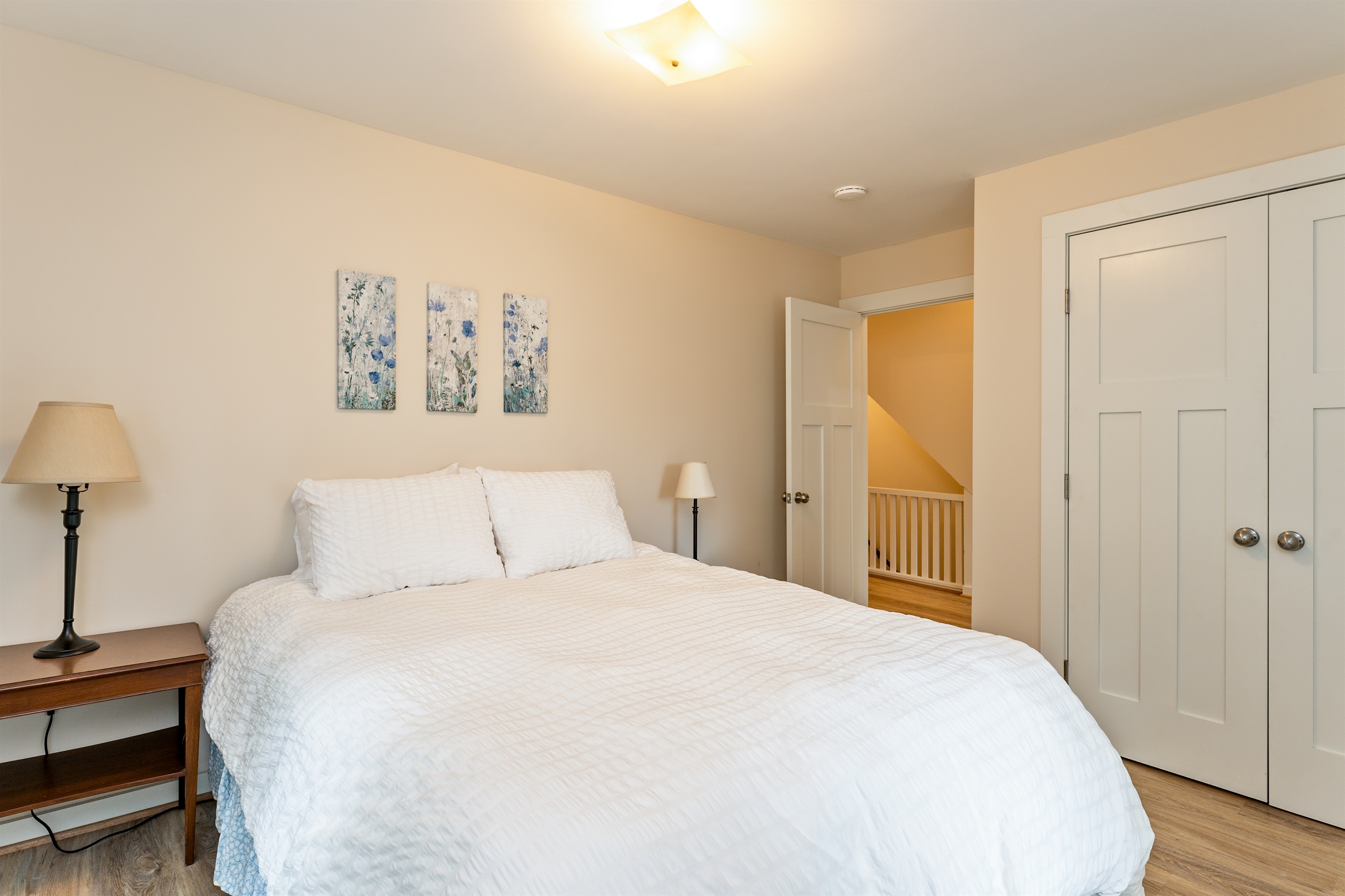 Inviting bedroom with serene views, soft natural light, and a plush white comforter for restful nights. Bedroom #1 queen