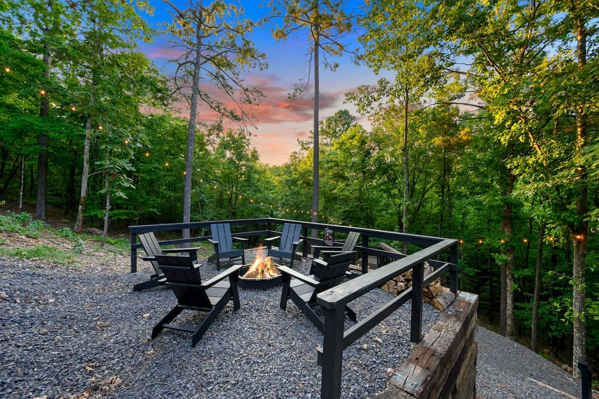 Firepit area with adirondack chairs and string lights.
