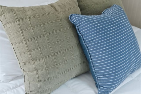 Close-up of plush bedding with soft linens and stylish accent pillows, creating a cozy and inviting sleep space.