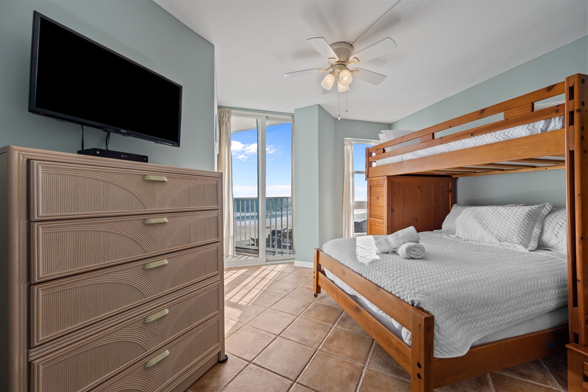 Second bedroom includes a dresser and TV, offering storage and entertainment with a coastal backdrop