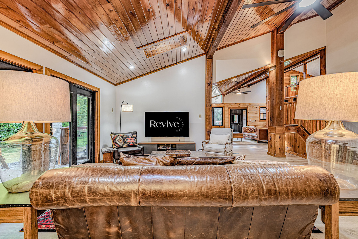 The light-filled main living room flows seamlessly to the expansive outdoor deck and connects to a second lounge, offering generous seating and a large TV for effortless gathering.