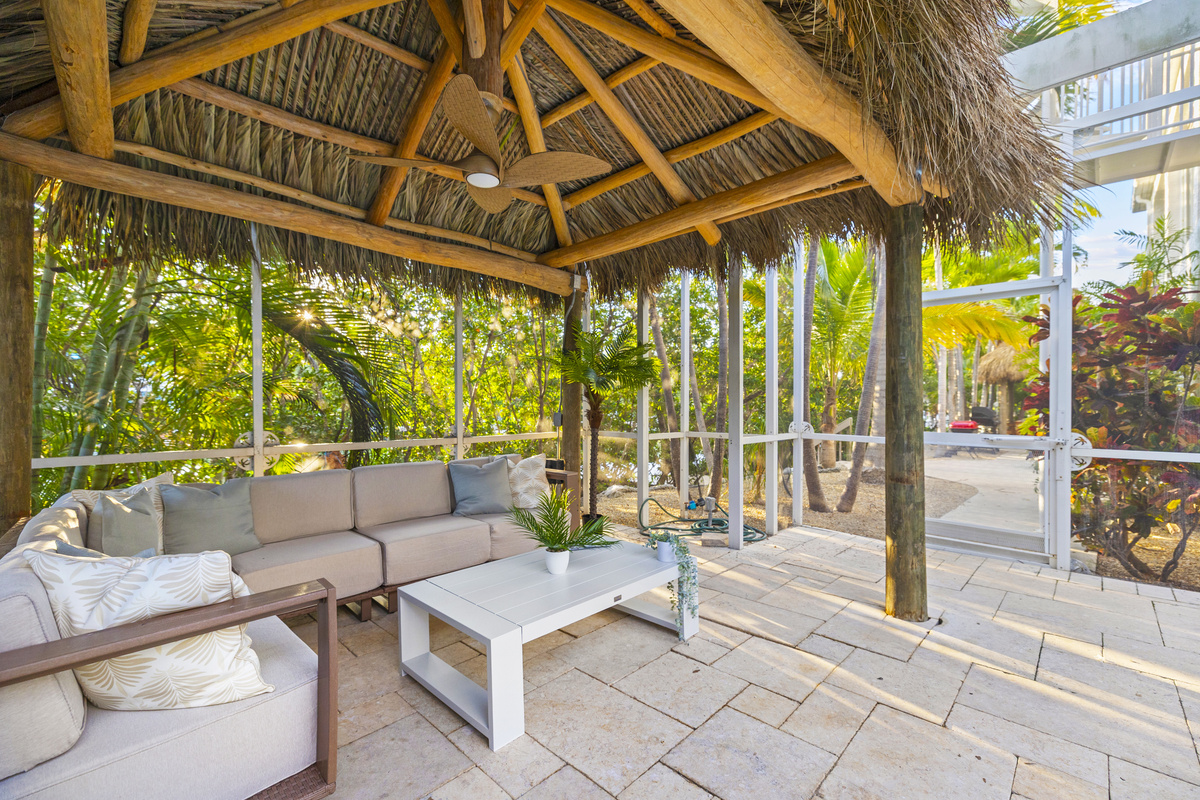 The second tiki hut is located inside the netted enclosure, next to the pool.