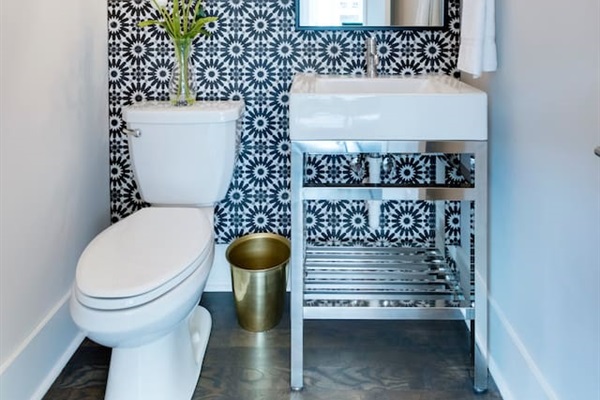 - Eye catching black and white floral wallpaper adds personality to this half bath - Sleek chrome vanity with open shelf and bold mirror elevate the modern vibe - Fresh florals, gold accent bin, and minimal décor create a polished guest space