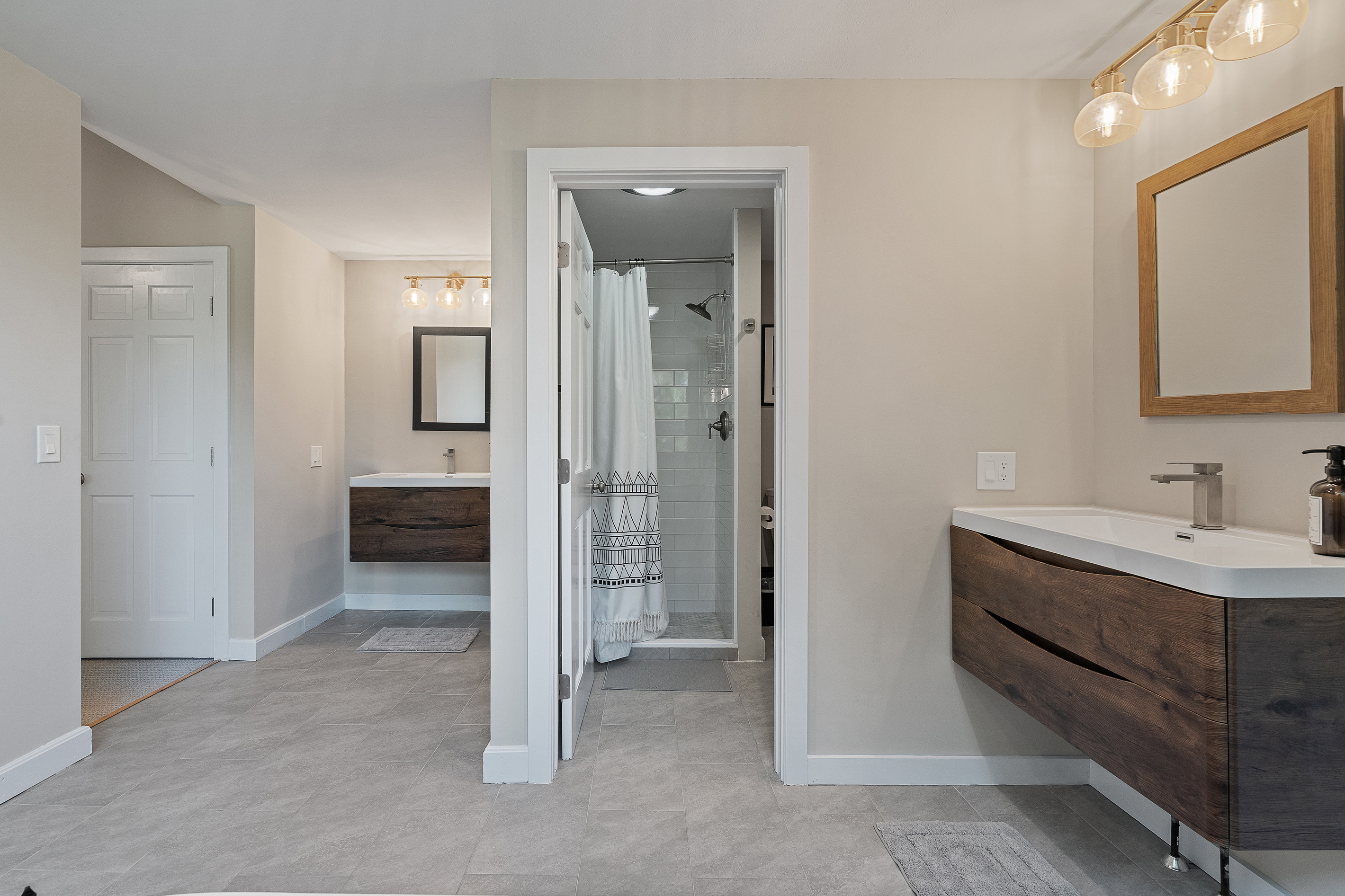 En-suite bathroom with floating wood vanity adjoining the primary bedroom
