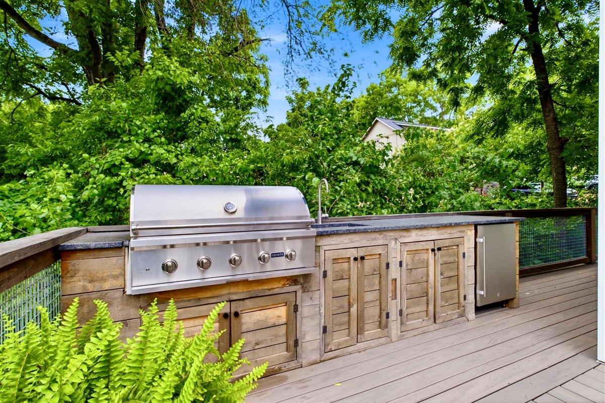 Built-in outdoor kitchen w/ a full-size grill & wood cabinetry ready for a serious cookout.
