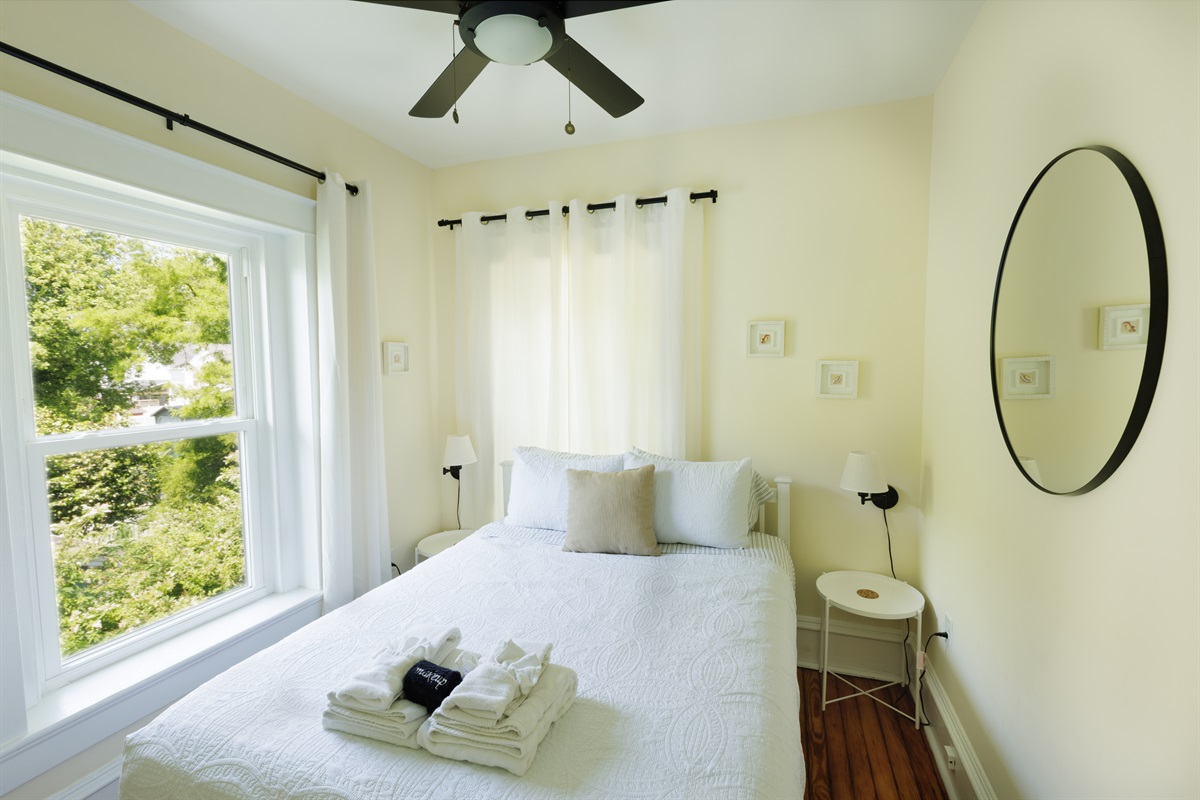 Queen bedroom with curtains and bedside lights for enjoying a book in the evening after a day at the beach.