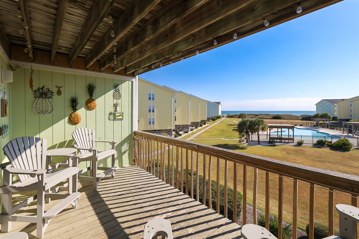 Enjoy sun-soaked views of the pool, landscaped grounds, and distant ocean right from your private balcony