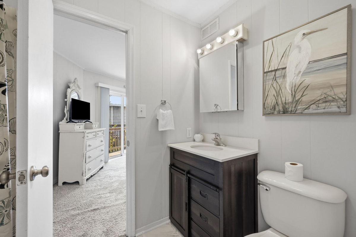 Bright full bathroom featuring a modern vanity, ample storage, and direct access to the adjoining bedroom