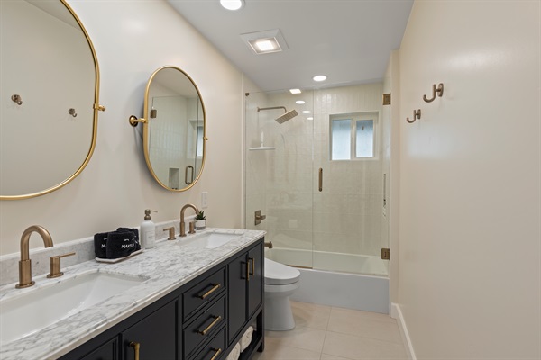 Bright and modern bathroom with dual sinks and a glass-enclosed tub and shower