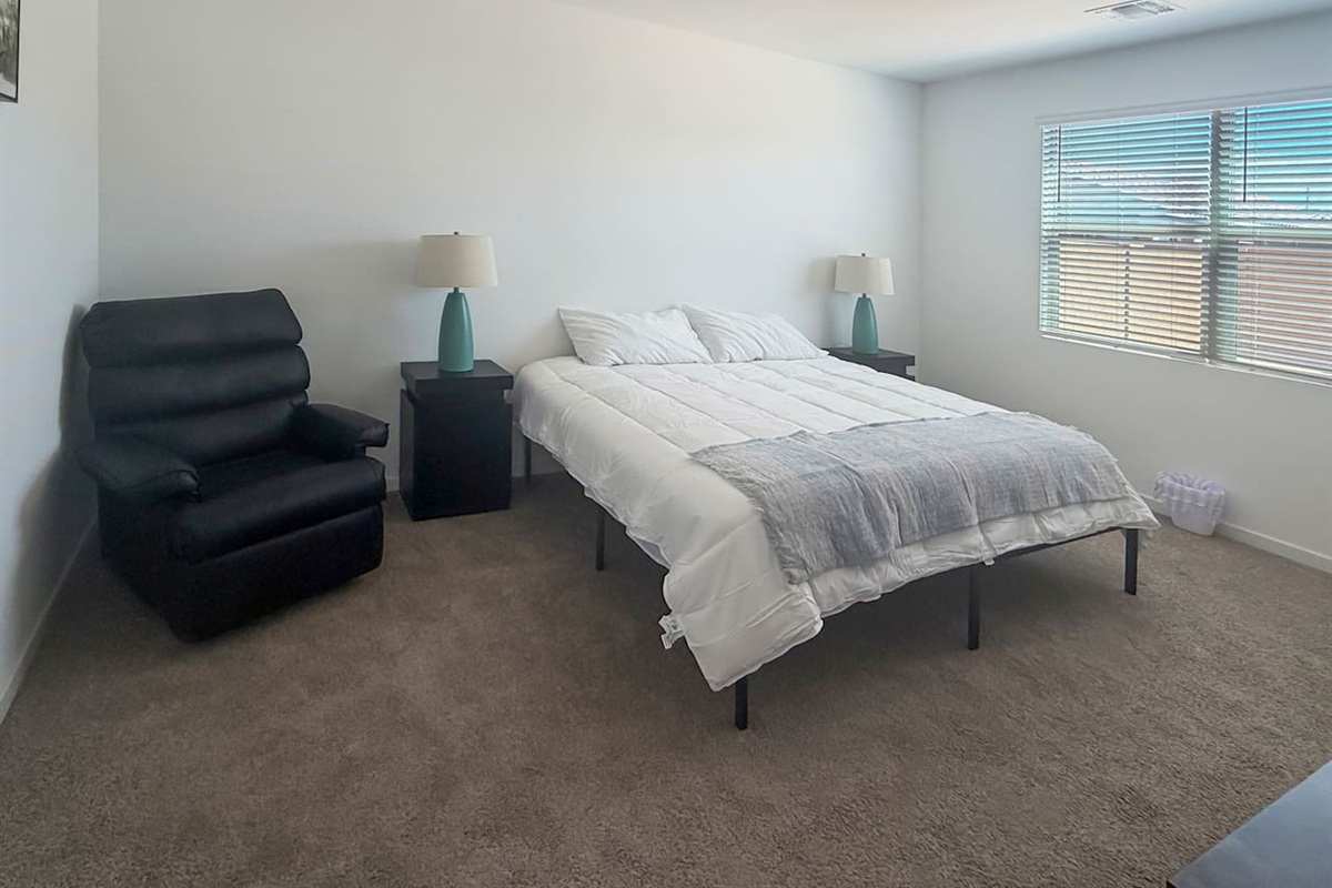 Bedroom with bed, recliner, nightstand, and windows