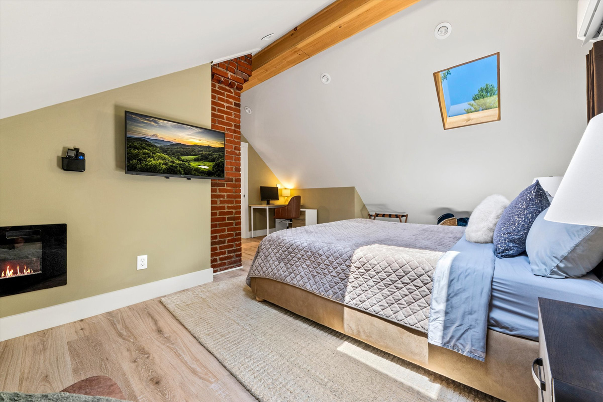 The Penthouse: Master Bedroom with King Bed, 42-inch Smart TV, Fireplace, sound machine, blackout curtains and cozy reading chair.