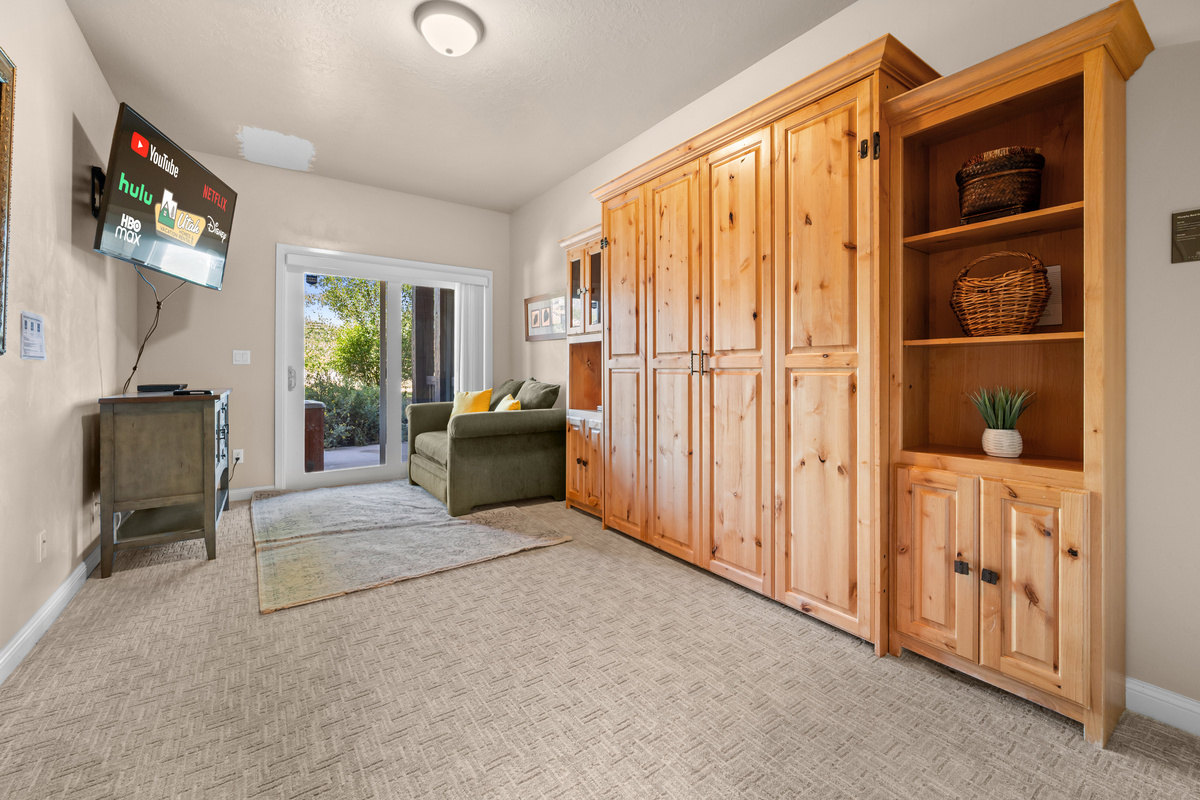 Versatile bedroom featuring a Murphy bed, seating area, and access to the outdoors.
