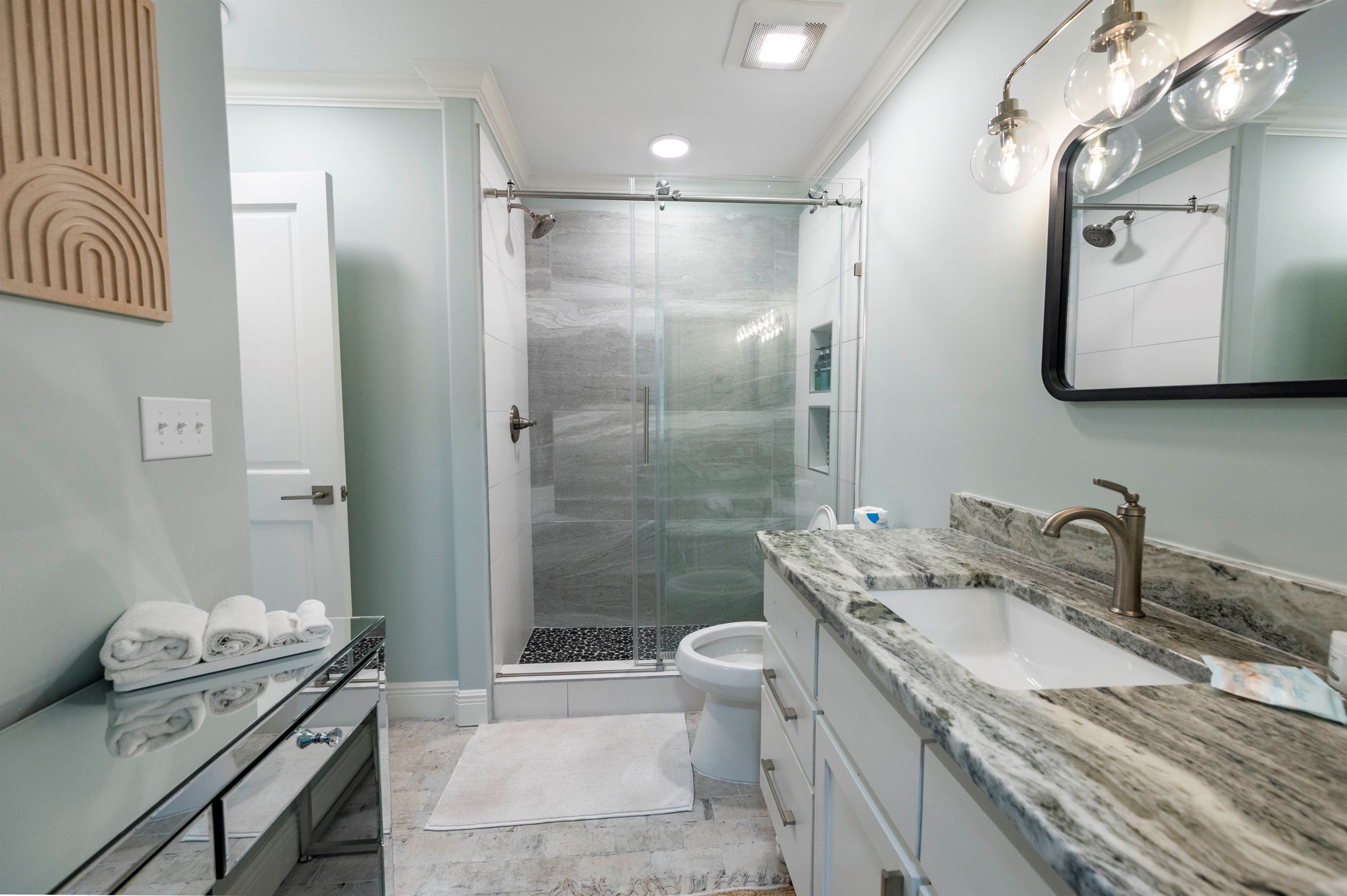 Modern bathroom with a glass shower, marble countertop, sleek lighting design, and a luxurious feel.

