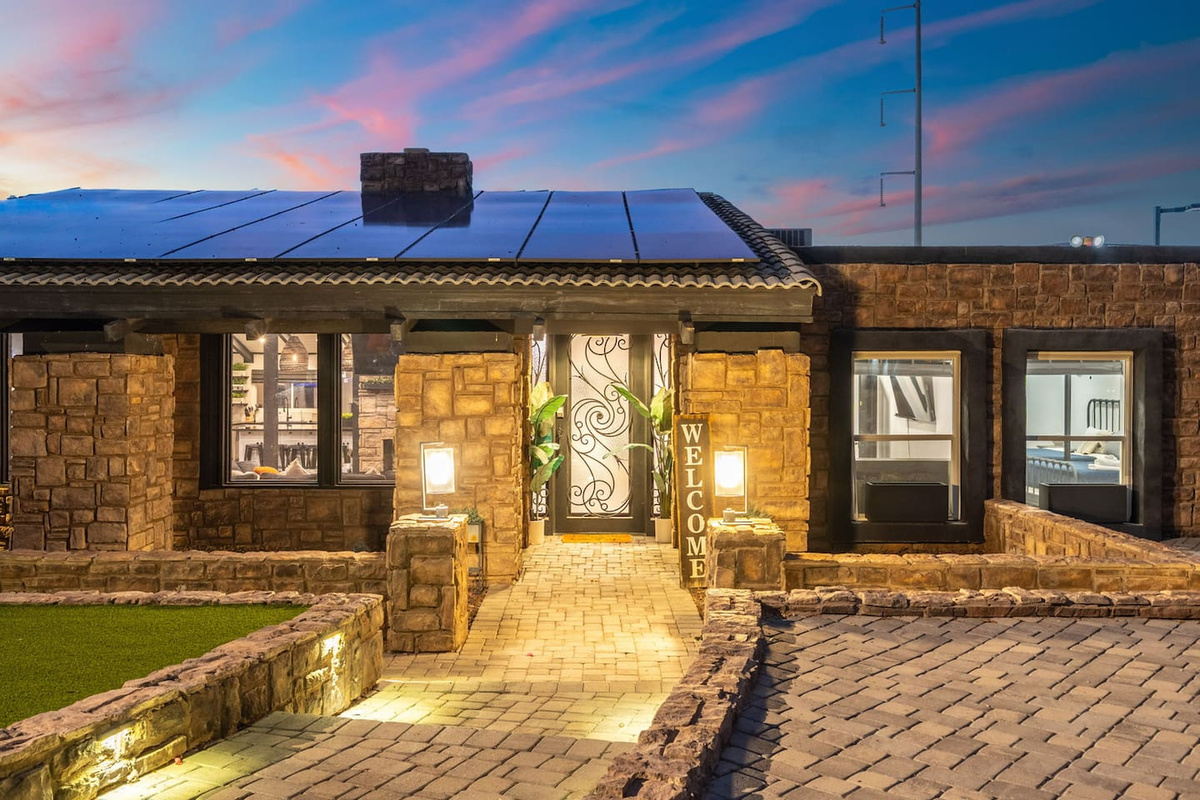 A stone-accented entryway glows under twilight skies, welcoming guests with warm lighting and desert charm.