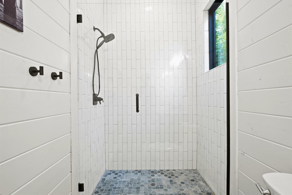 Modern and streamlined, this bathroom features a spacious, walk-in shower with chic tiling and crisp white walls