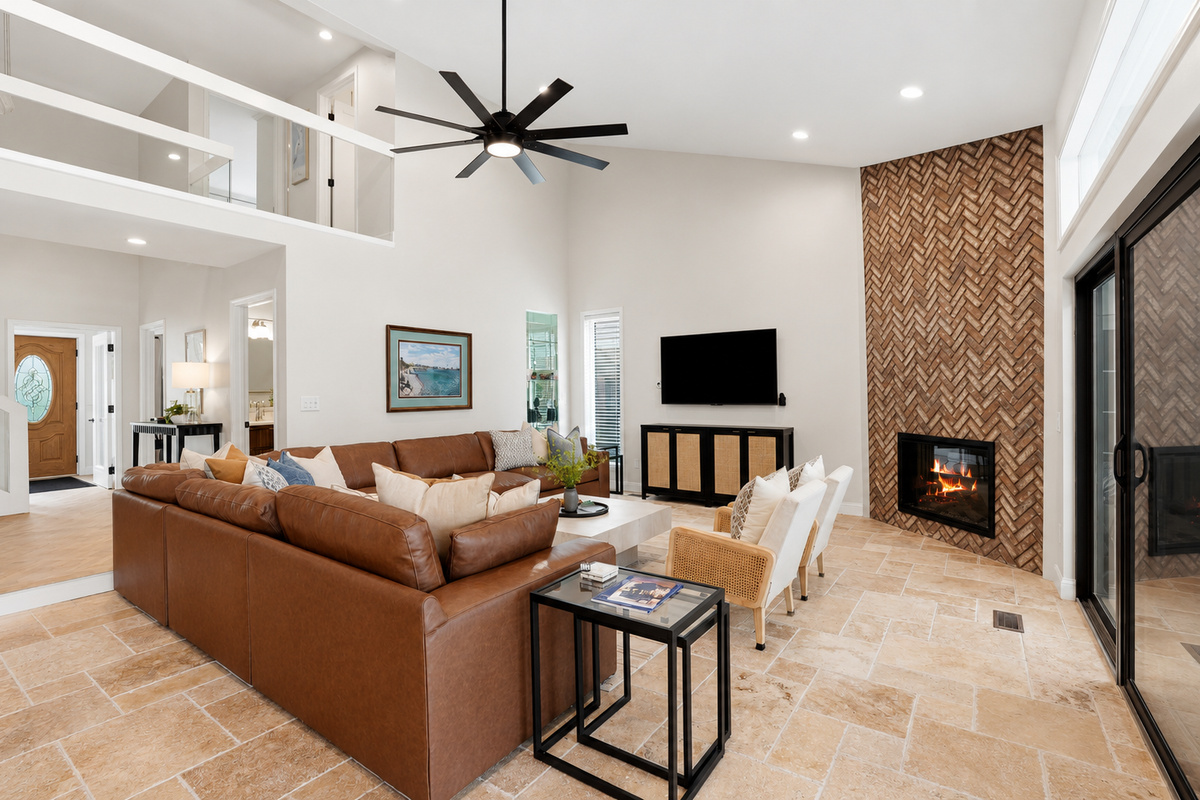 Spacious open-concept living room with a cozy sectional, modern fireplace, and high ceilings. Bright, stylish space ideal for relaxing, entertaining, and enjoying group stays.