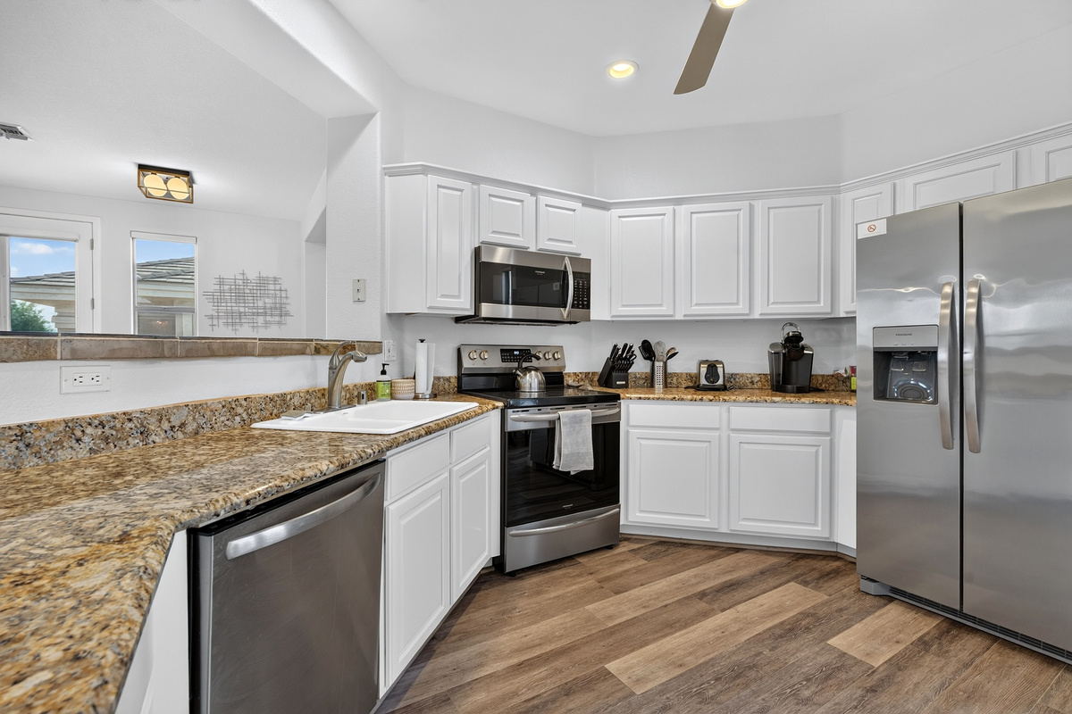 Kitchen with stainless steel appliances, dishwasher, granite counters, and open views into the living area.