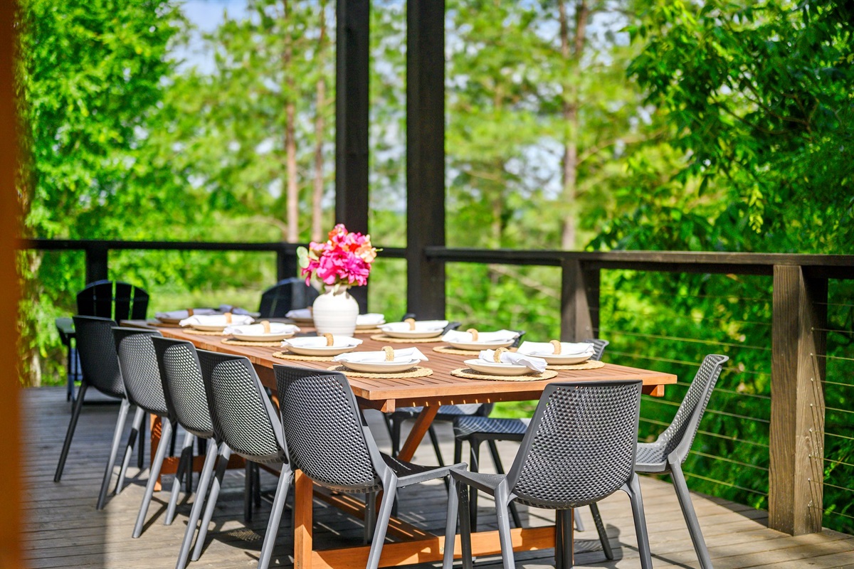 Spacious outdoor dining table set against lush forest backdrops.