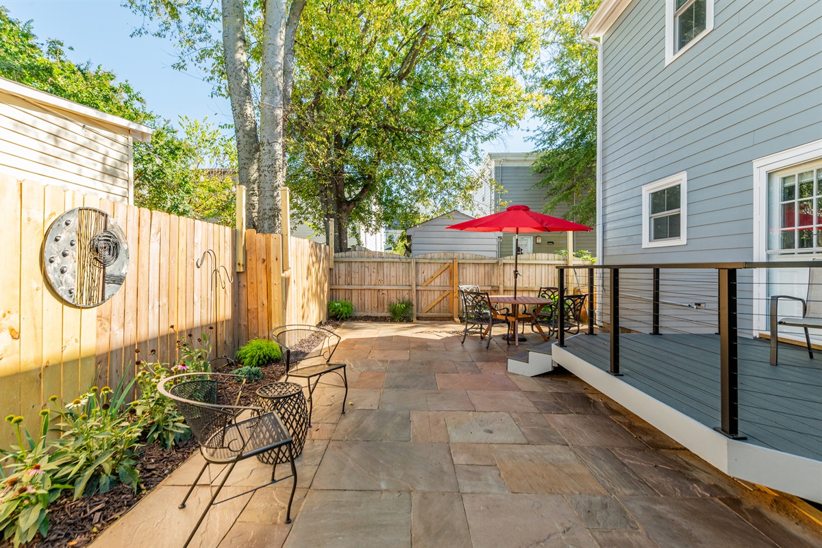 Outdoor Oasis: Enjoy al fresco dining under the vibrant red umbrella in a lush, private retreat!