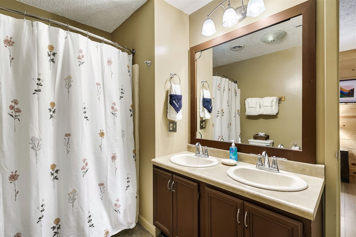 Bathroom with shower/tub combo and two sinks.