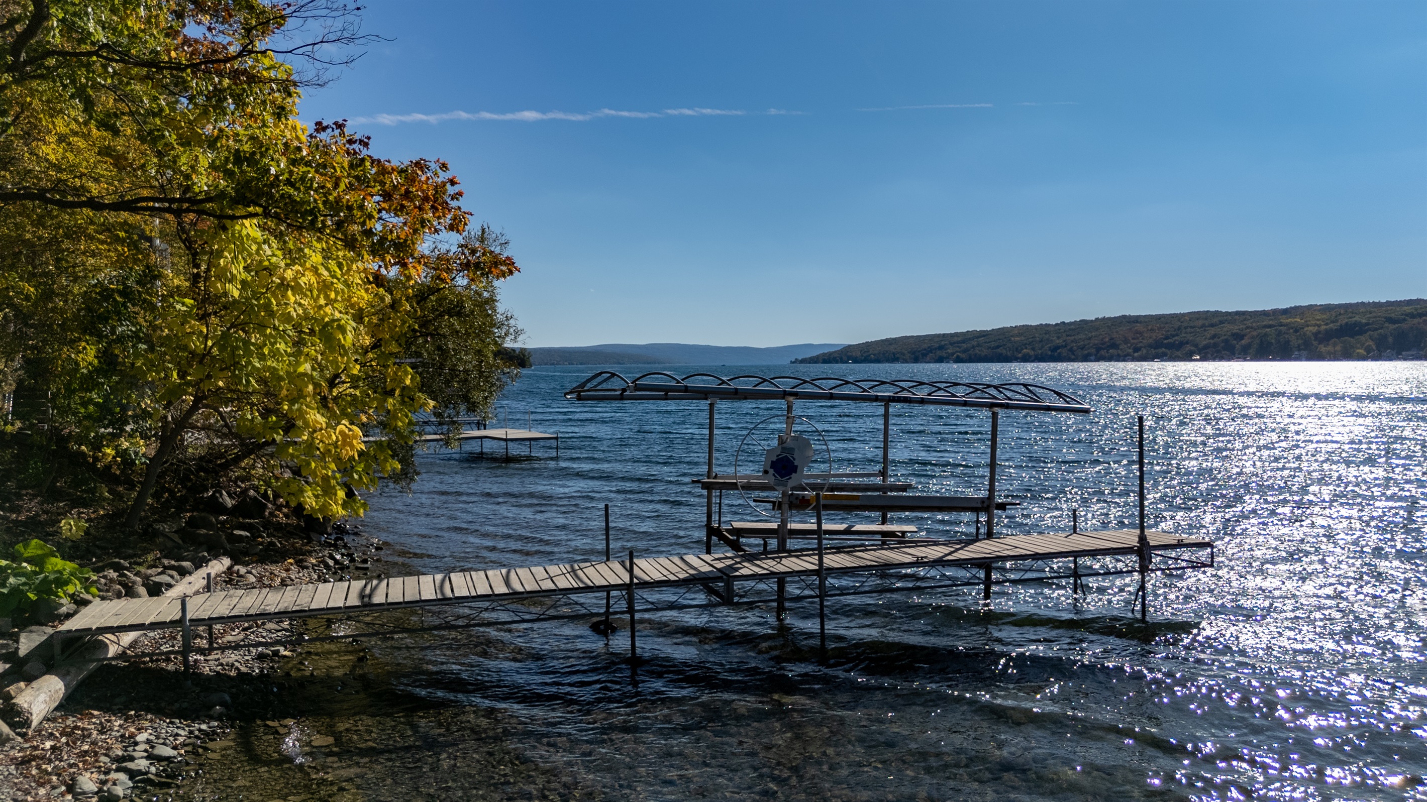 Dock extending into the sunlit lake — early morning or golden hour mood.
