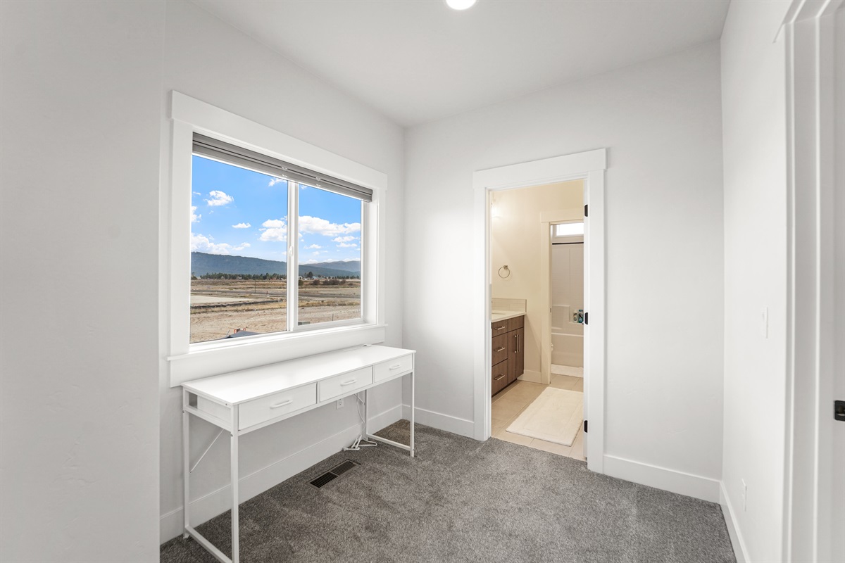 Convenient desk space and natural light, connected to a full bath.