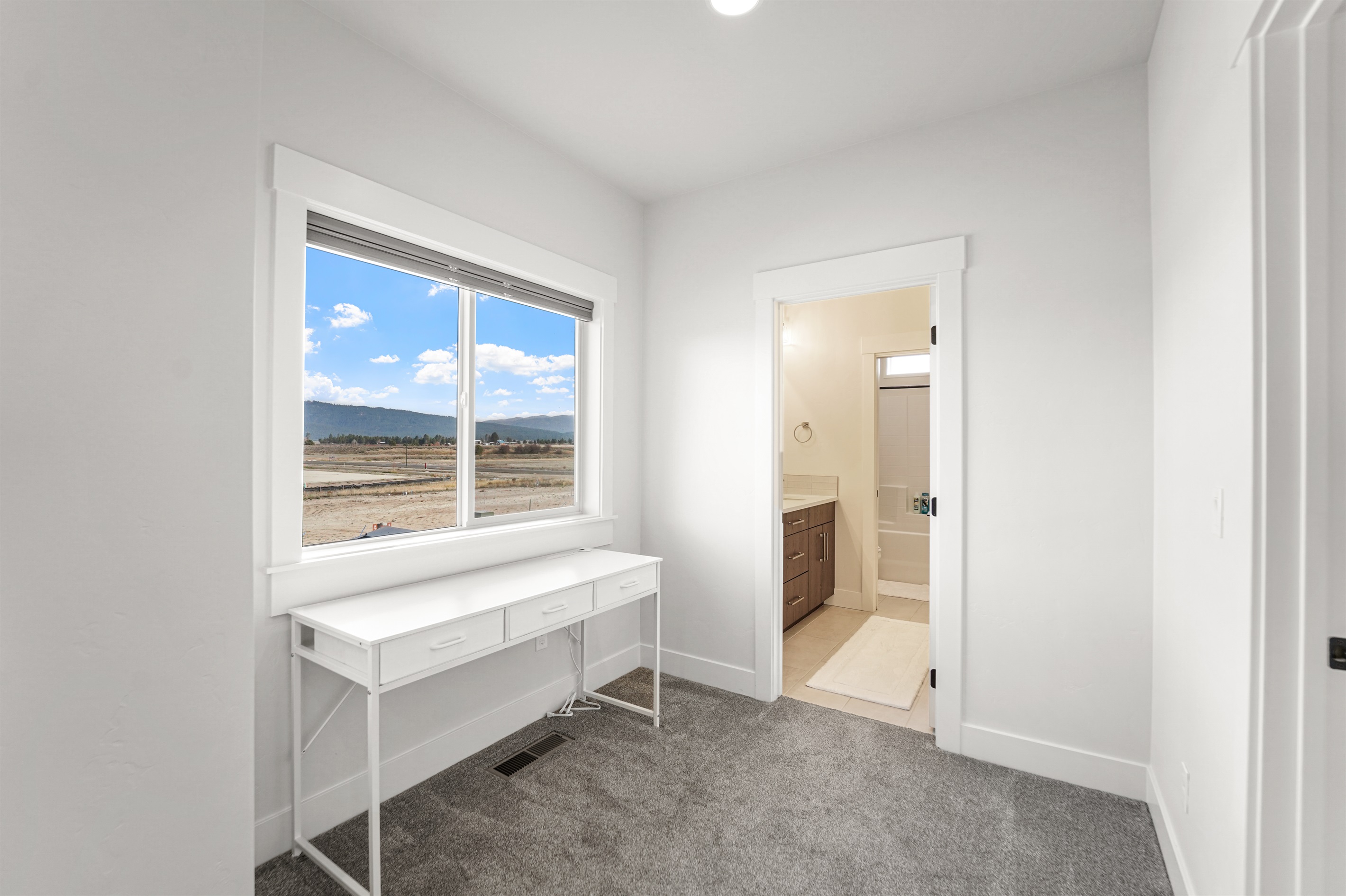 Convenient desk space and natural light, connected to a full bath.