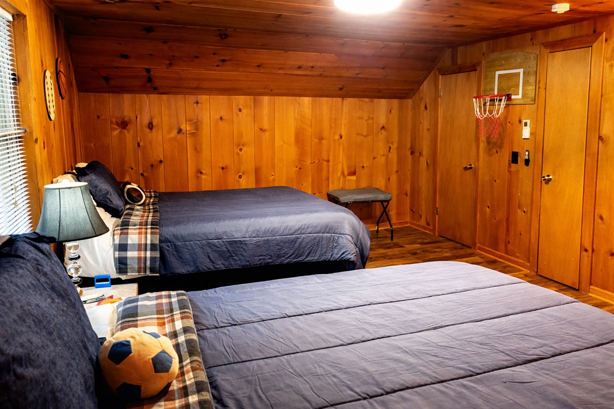 Cozy cabin bedroom with two comfortable beds and a fun mini basketball hoop — perfect for families or kids.