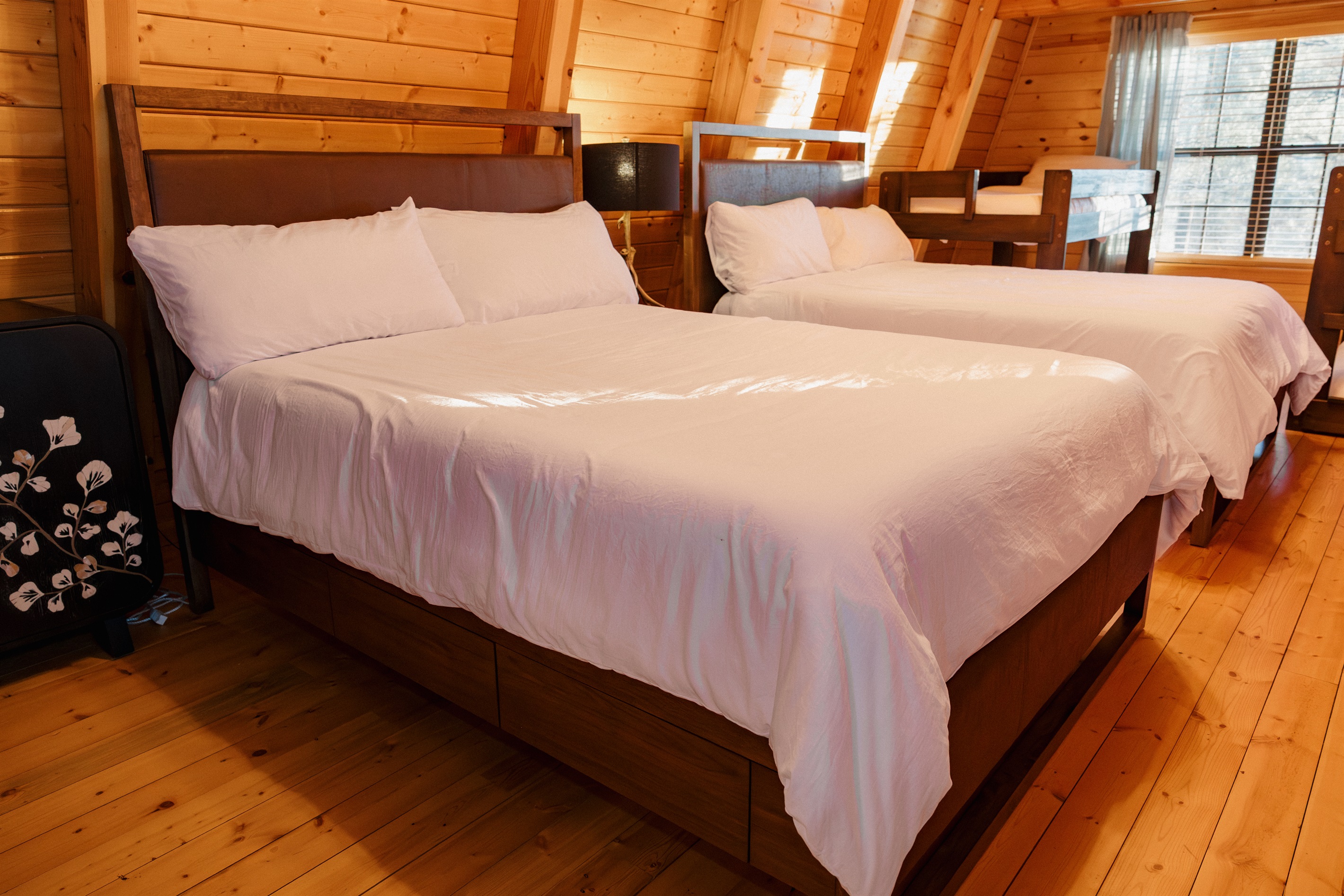 Two queen beds with crisp linens in the Big Bedroom at Poppywood Pines, complete with climate-controlled split unit. This spacious Show Low loft sleeps families comfortably, perfect for restful nights after exploring White Mountains hiking and fishing.