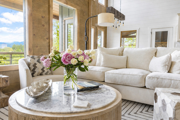 The expansive windows give breathtaking sunset views! Sink into plush white sofas and chairs around the warm fire — the perfect spot for relaxing after a day of adventure.
