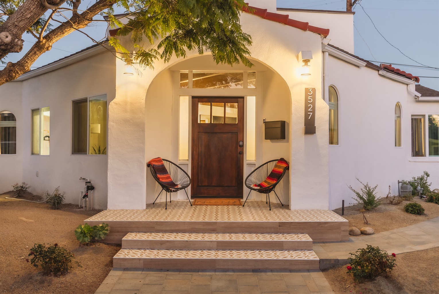 Charming Entrance: Relax on chairs by the stylish doorway of this Spanish style home under San Diego's warm sun!