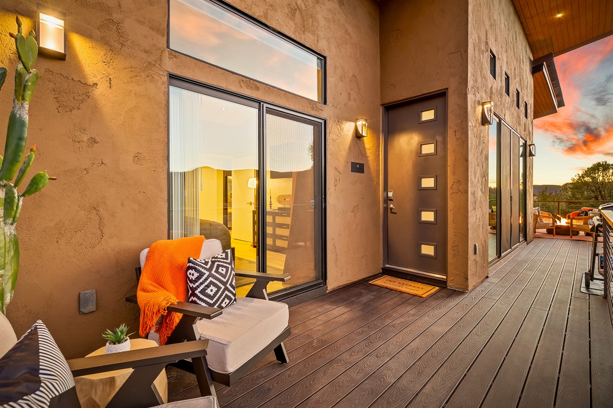 A welcoming private deck at the front door, with comfortable seating and warm evening lighting that sets a calm, intentional transition into the retreat after a day exploring Sedona.